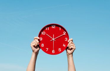 Zwei Armei halten eine Uhr hoch.