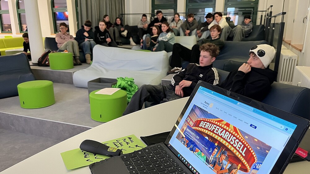 Schüler sitzen auf grünen Sofas im Vorraum zum DLR School Lab.