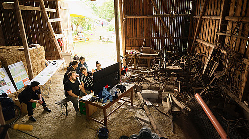 Symbolbild für die Citizen-Science-Methode „Landinventur“: Mehrere Menschen arbeiten mit moderner Technik in einer Scheune.