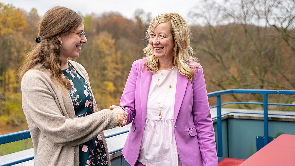 Claudia Döring und Professorin Keil schütteln Hände auf einer Dachterrasse.