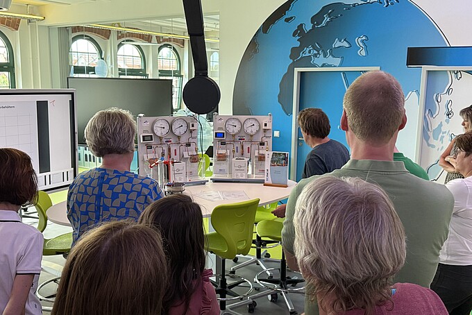 Lehrer und Lehrerinnen stehen im Schülerlabor vor Versuchsständen.