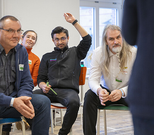 Eine Gruppe diskutiert. Einer hält seine Hand hoch.