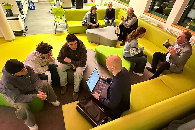Schüler sitzen auf Sofas und unterhalten sich mit einem Berater.