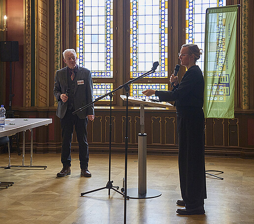 Professor Kästner steht neben einer Vortragenden.