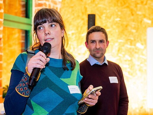 Julia Gabler spricht in ein Mikrofon, daneben steht ein Mitarbeiter.