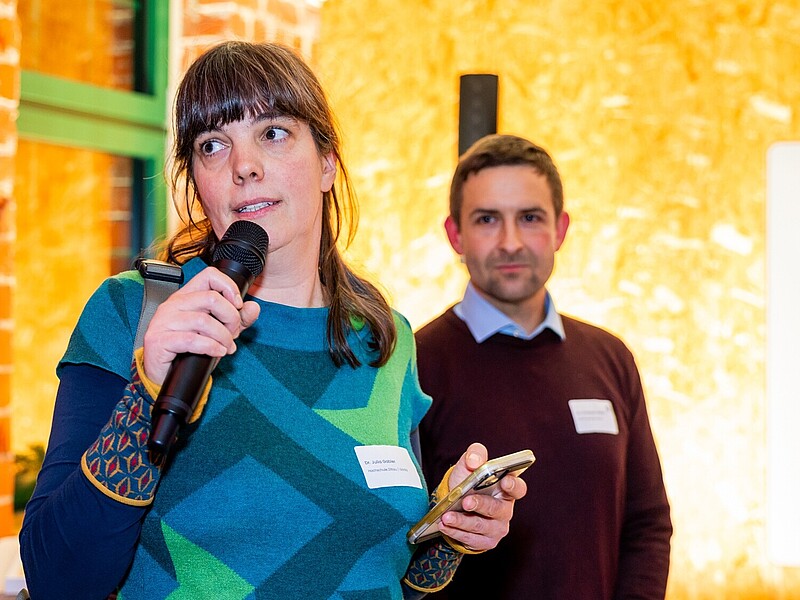 Julia Gabler spricht in ein Mikrofon, daneben steht ein Mitarbeiter.