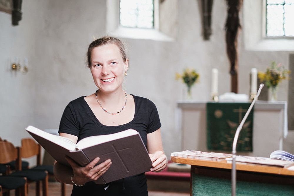 Frau Mahling sitzt in Kirchenbank, mit aufgeschlagener Bibel