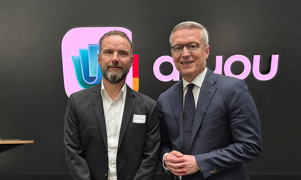 Lars Rönisch und Bundesdigitalminister Dr. Karsten Wildberger stehen vor einer Wand mit dem Logo der digitalen Identitäts-Wallet d-you.