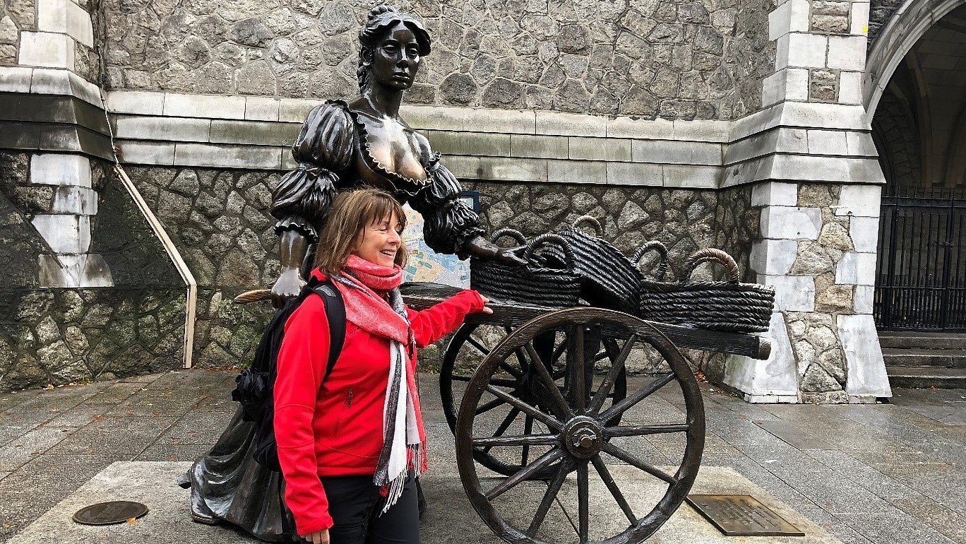 Frau Kunze lehnt an eine Statue und lacht.