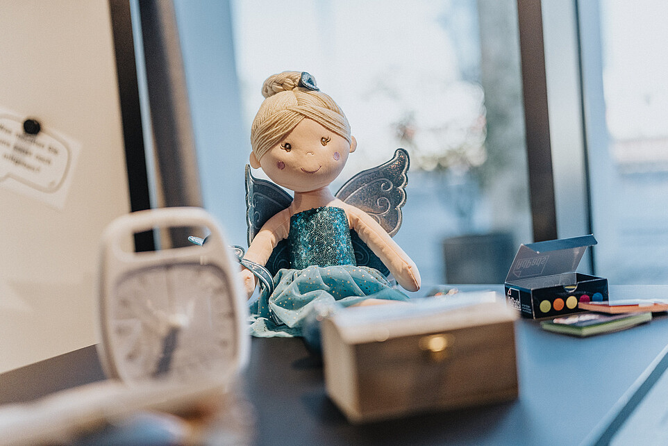 A small doll next to an alarm clock